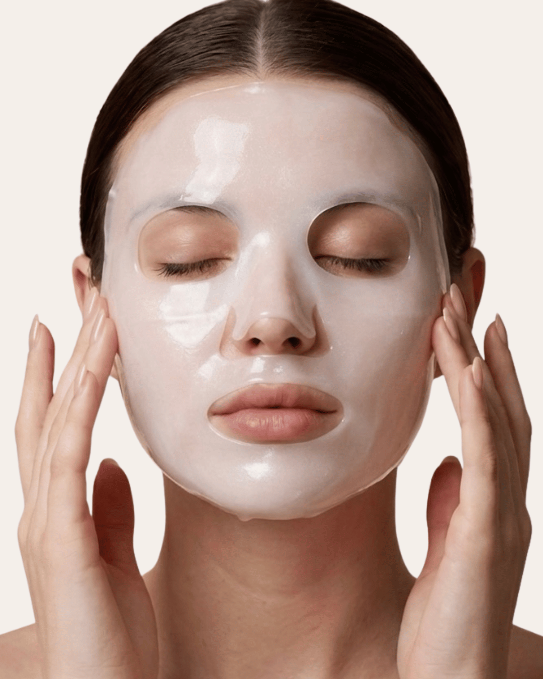 Woman applying a facial mask with a neutral background